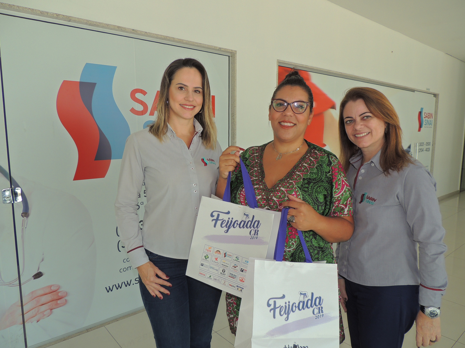 Cláudia Teixeira e Andréa Poggianella ladeando Diana Pires, contemplada com duas camisetas da Feijoada 2019 na promoção do Instagram do Sabin Sinai, que teve mais de três mil comentários