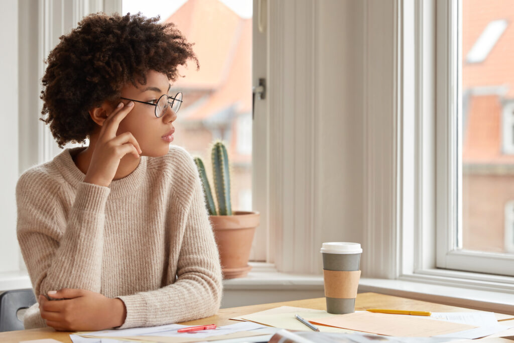 O empreendedorismo como um objetivo carreira para as novas gerações 2 photo of contemplative woman with afro hairstyle wears round spectacles casual warm sweater