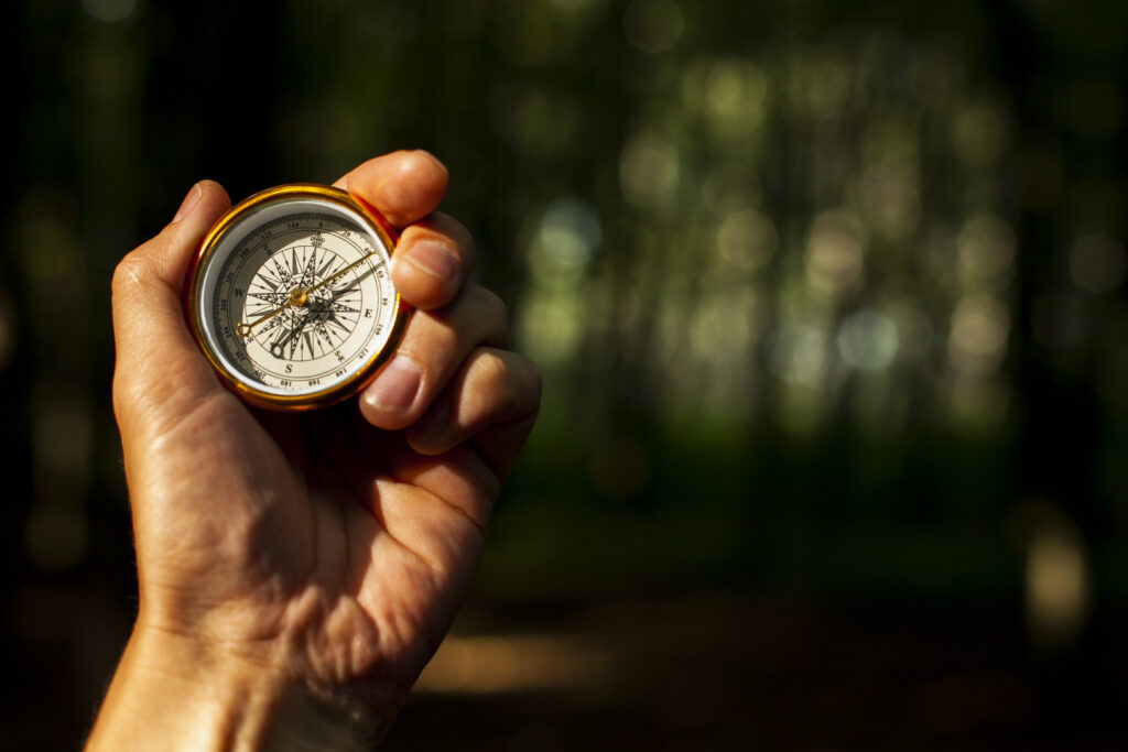 Valores e propósitos: você conhece a importância desses dois pilares para pessoas e empresas? 2 hand holds compass with blurred background
