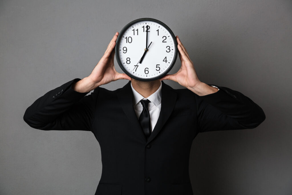 Gestão do tempo: planejar e priorizar para ser produtivo 2 young man black suit holding clock front his face