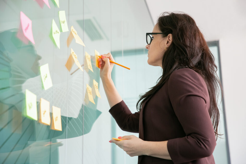 Principais insights e as 10 habilidades mais importantes segundo Fórum Econômico Mundial 2023 2 mulher de negocios de meia idade confiante escrevendo em um adesivo com lapis e brainstorming