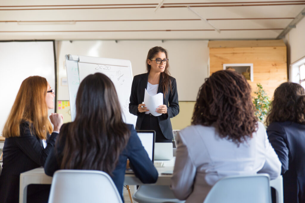 Você realmente sabe se comunicar? 2 businesswomen looking speaker with papers