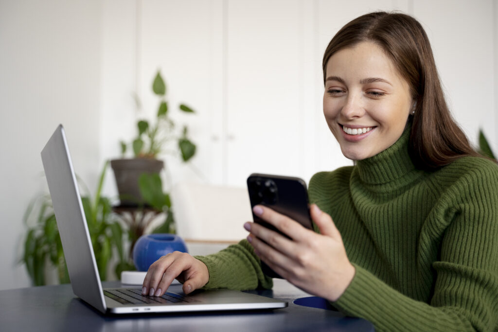 A importância de proteger seus dados pessoais e empresariais com backups seguros 2 woman talking her smartphone using handsfree feature writing something her laptop