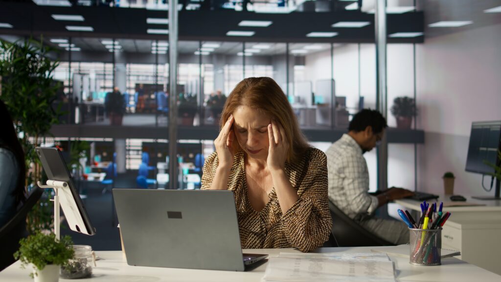 Burnout: a exaustão emocional de viver no automático e esquecer de si mesma 1 successful woman battles headache while managing her financial projects