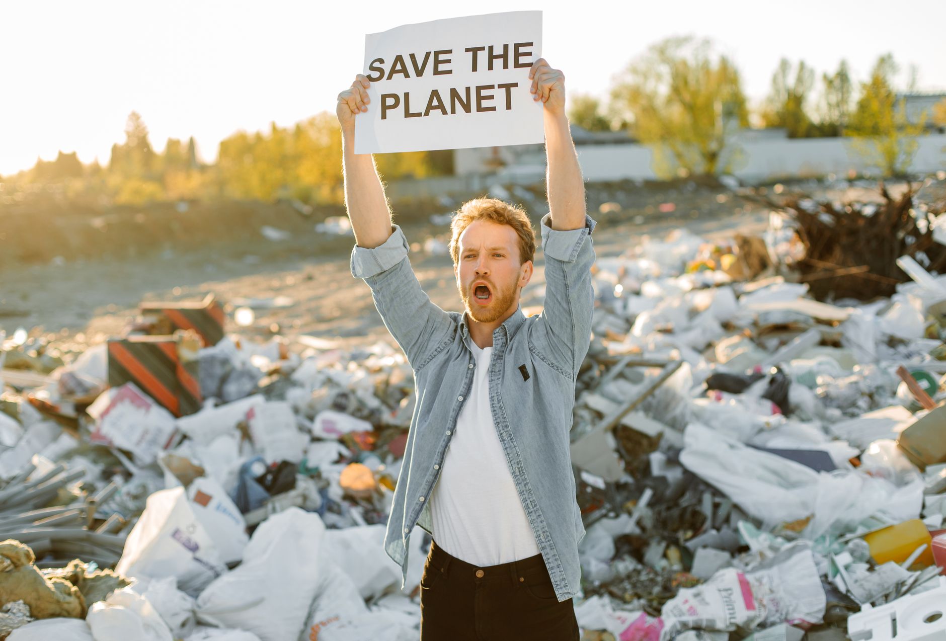 Cientista alerta que uma nova extinção em massa já pode estar acontecendo e seria a mais rápida da história, com mudanças no clima acelerando o desaparecimento de espécies 1 Ativista apaixonado segurando placa para salvar o planeta em um lixão, promovendo a conscientização ambiental.