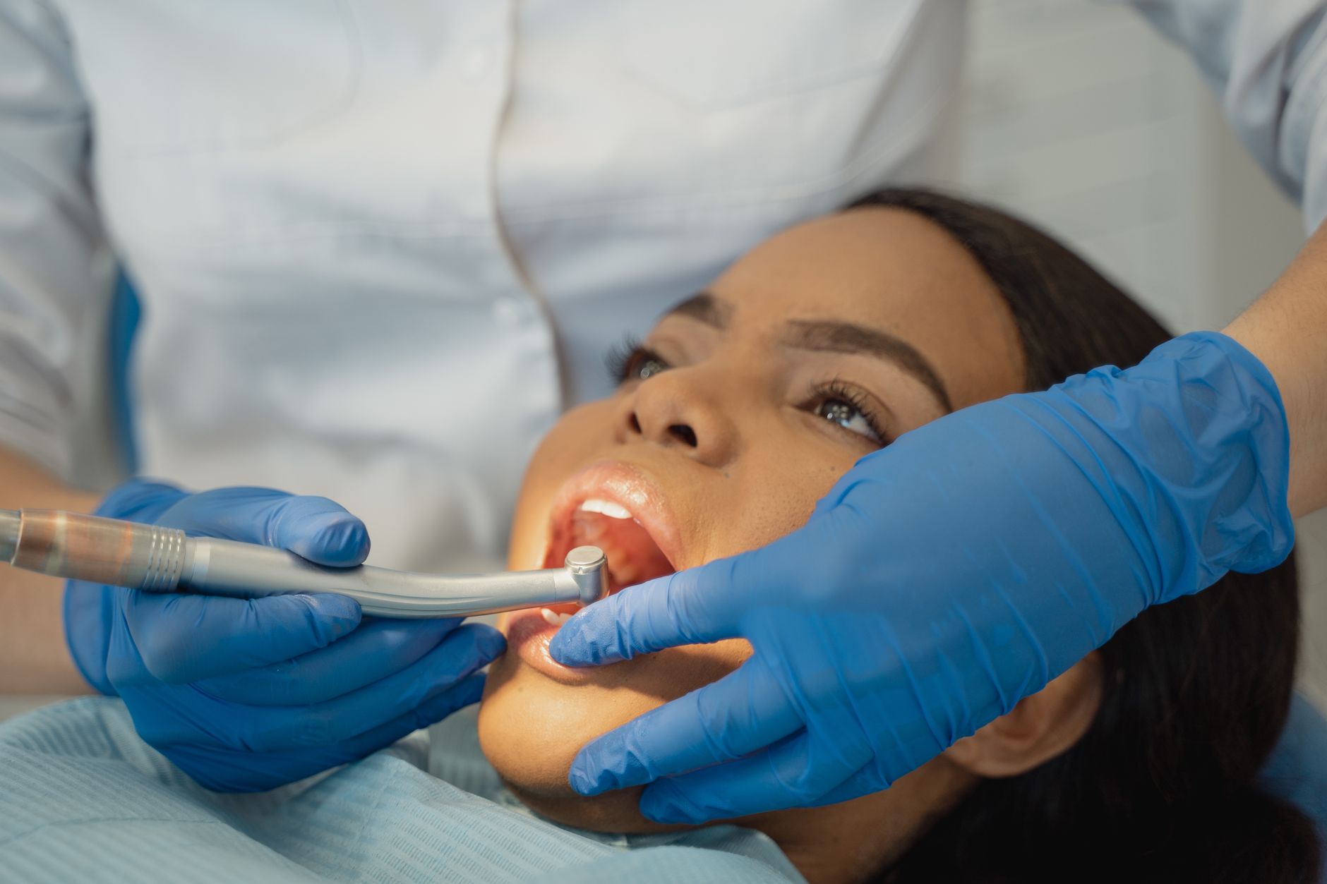 Dentista explica por que passar o fio dental rapidamente entre os dentes não é suficiente e ensina técnica que remove a placa e ajuda a prevenir o mau hálito 2 Close-up de um dentista realizando um tratamento dental em um paciente.