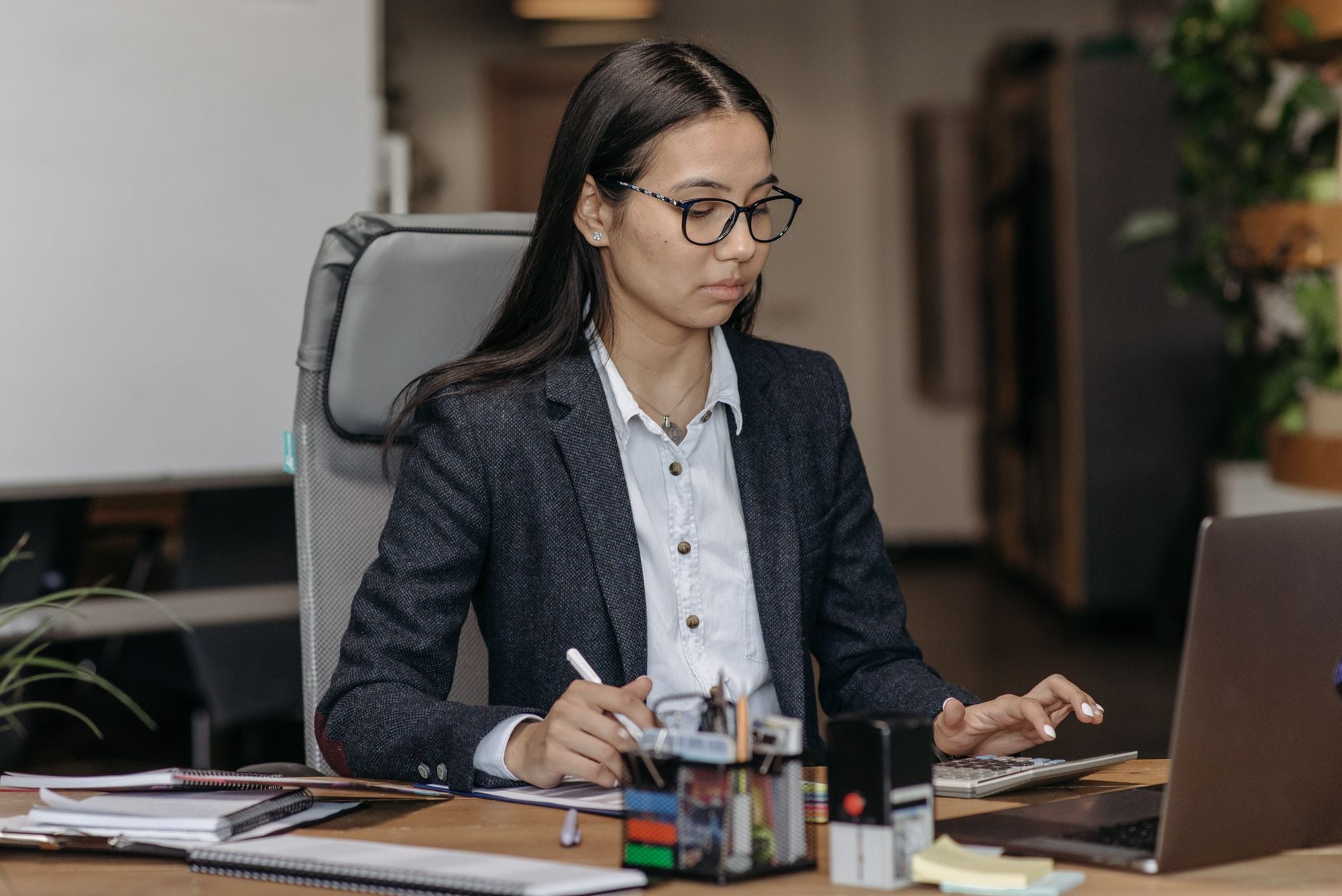 Depois de anos trabalhando na empresa, funcionária finalmente tentou conseguir a promoção que queria, mas acabou descobrindo uma decisão da empresa que mudou completamente seus planos 1 Jovem mulher trabalhando com concentração em seu laptop em um ambiente de escritório moderno, usando óculos.