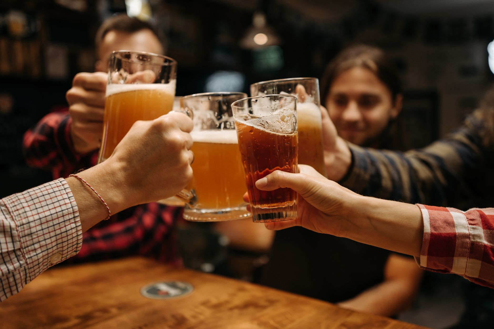 Enquanto moradores de alguns estados terão que passar parte do domingo sem comprar ou consumir bebidas alcoólicas, outros poderão frequentar bares normalmente durante o primeiro turno das eleições 3 Brinde celebratório com canecos de cerveja entre amigos em ambiente fechado, capturando diversão e amizade.