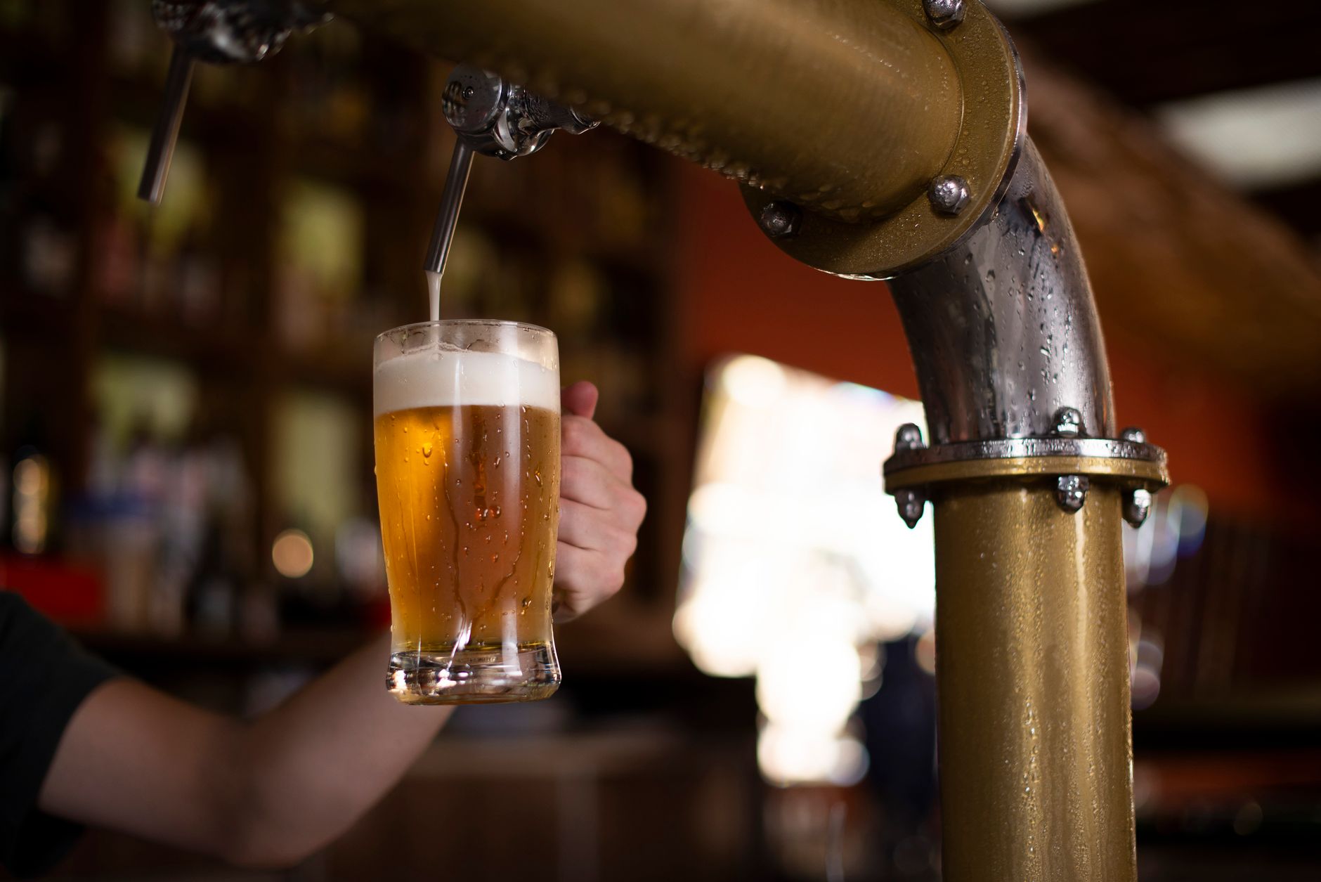 Enquanto moradores de alguns estados terão que passar parte do domingo sem comprar ou consumir bebidas alcoólicas, outros poderão frequentar bares normalmente durante o primeiro turno das eleições 5 Um close de uma mão segurando um caneco enquanto a cerveja é despejada de uma torneira de cervejaria.