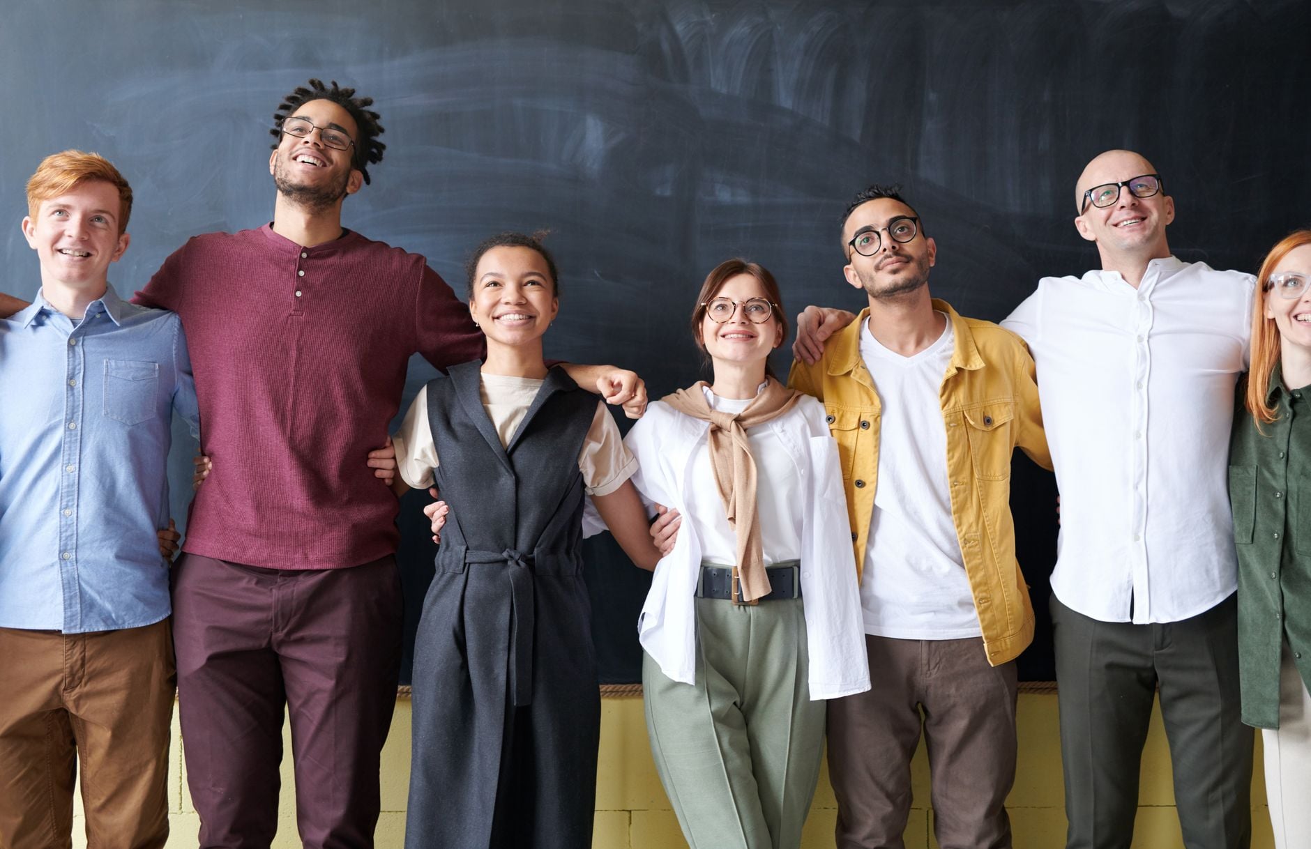 “Eu deveria ter feito isso antes”: pessoas com mais de 30 anos compartilham arrependimentos e conselhos que gostariam de ter recebido quando eram mais jovens 1 Um grupo diverso de colegas se abraçando alegremente em um ambiente de escritório, mostrando espírito de equipe.
