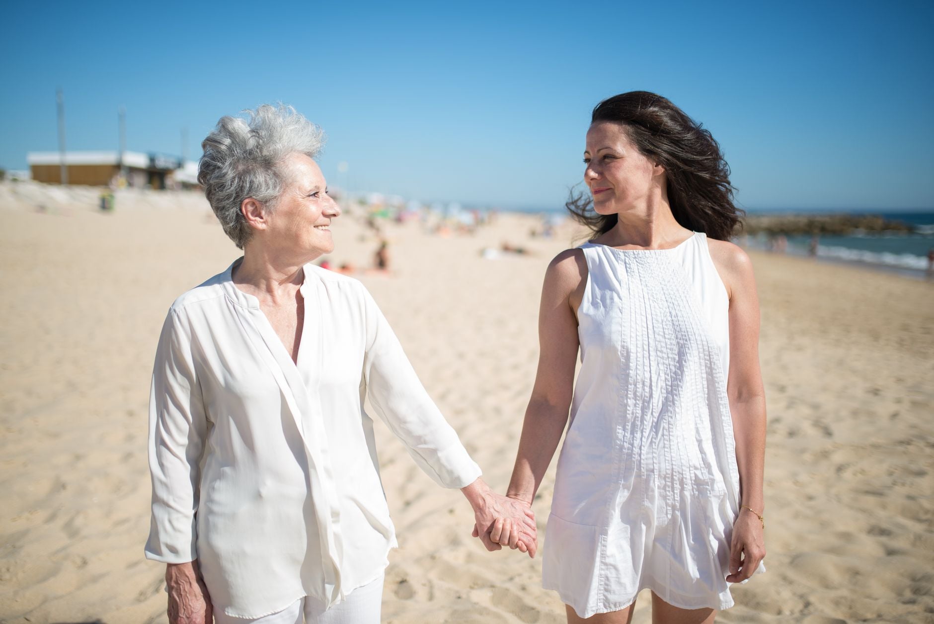 “Eu deveria ter feito isso antes”: pessoas com mais de 30 anos compartilham arrependimentos e conselhos que gostariam de ter recebido quando eram mais jovens 5 Momento alegre de uma mãe e filha de mãos dadas em uma praia ensolarada em Portugal.