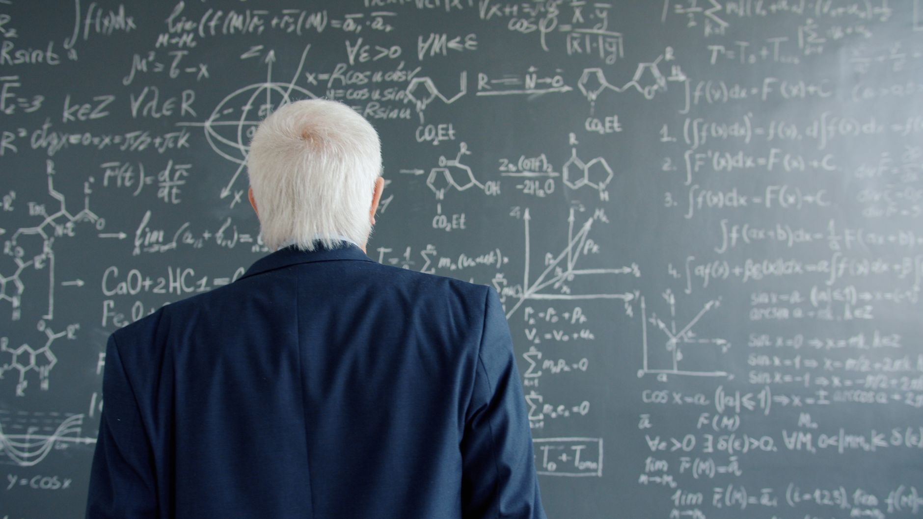 Filósofo explica a ideia de Platão que pode mudar a forma como você enxerga a felicidade: talvez estar realizado não signifique ter todas as respostas 1 Um cientista examina fórmulas matemáticas e químicas em um quadro-negro.