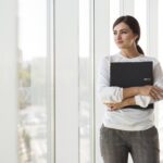 Por que o mercado ainda trata pausas na carreira como problema? 2 front view businesswoman posing while holding binder