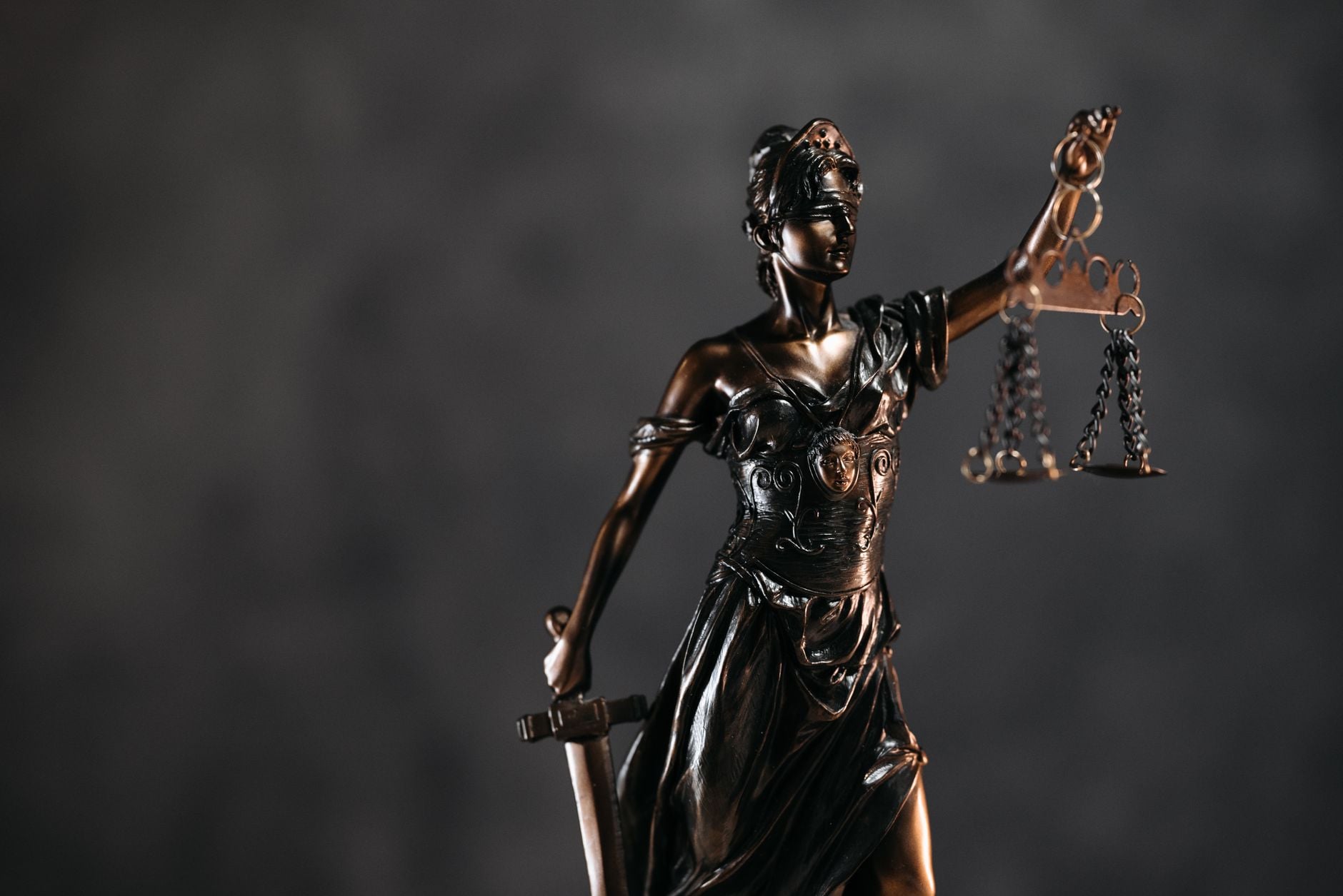 Pai doou parte de uma casa ao filho, mas anos depois enfrentou o agravamento de um câncer e decidiu recorrer à Justiça para tentar recuperar o imóvel 1 Estátua detalhada em bronze da Senhora Justiça com balança e espada contra um fundo escuro, simbolizando a lei e a justiça.