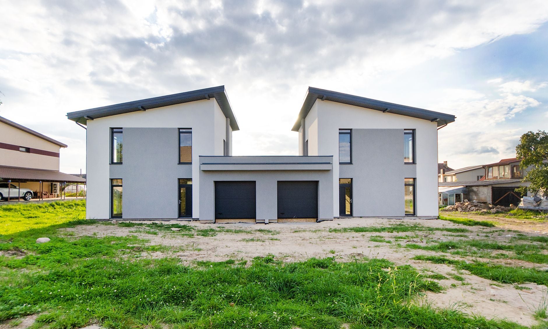 Pai doou parte de uma casa ao filho, mas anos depois enfrentou o agravamento de um câncer e decidiu recorrer à Justiça para tentar recuperar o imóvel 2 Vista frontal de casas gêmeas modernas com um design arquitetônico simétrico sob um céu nublado.