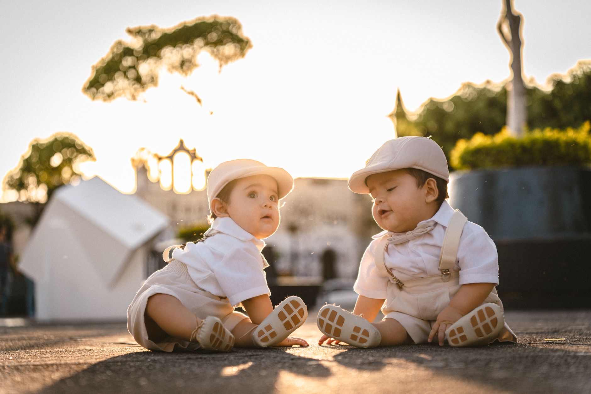 Pais brasileiros estão buscando nomes cada vez mais diferentes para os filhos, e três tendências que envolvem luxo, internet e futebol devem ganhar força em 2027 3 Gêmeos em adoráveis roupas brancas sentados ao ar livre ao pôr do sol, exalando fofura e calor.