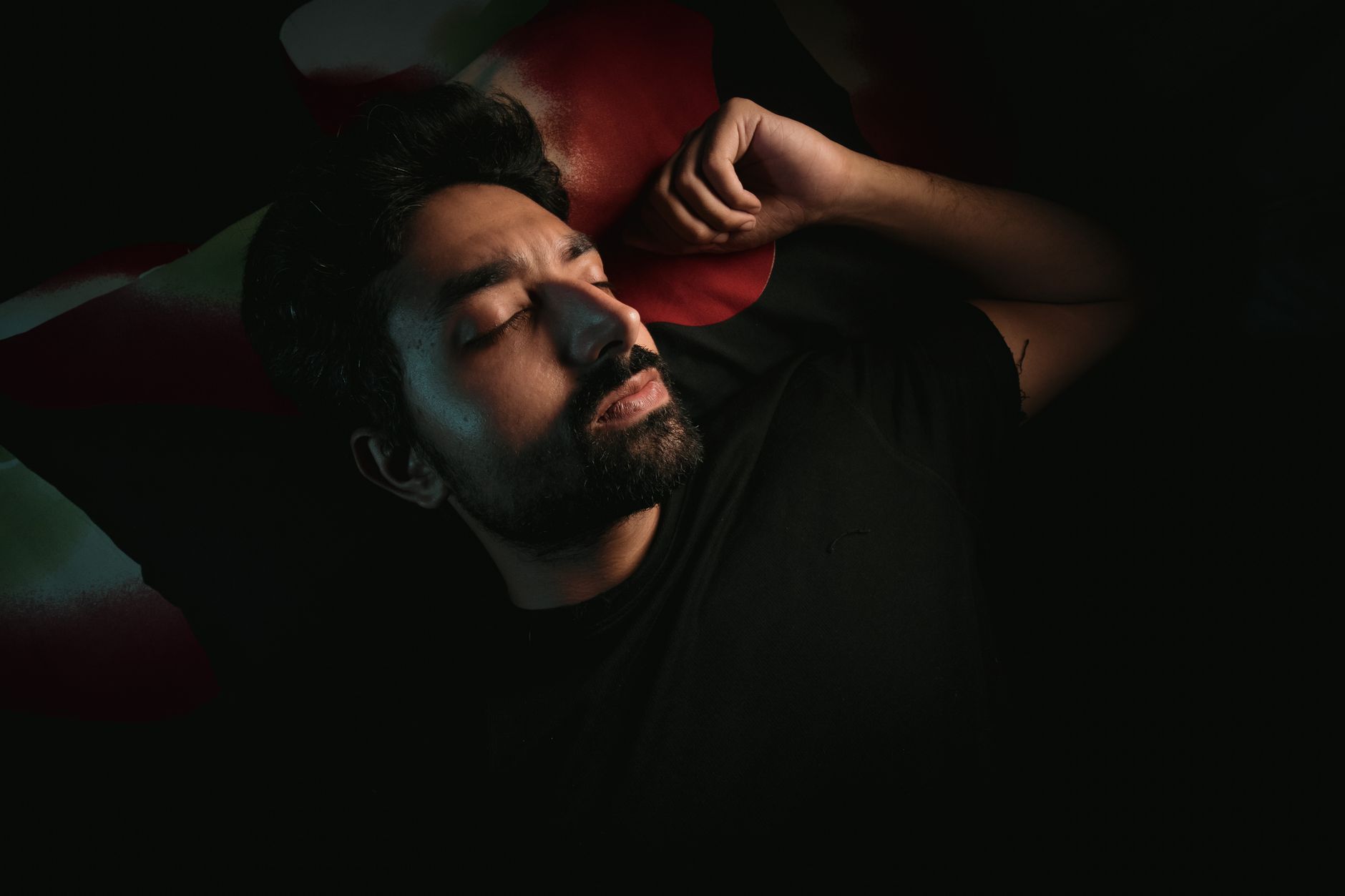 Por que algumas pessoas conversam, respondem e até gritam enquanto estão dormindo? Especialista explica o que pode estar por trás do comportamento 1 Um homem barbudo deita em um quarto pouco iluminado, descansando pacificamente com os olhos fechados.