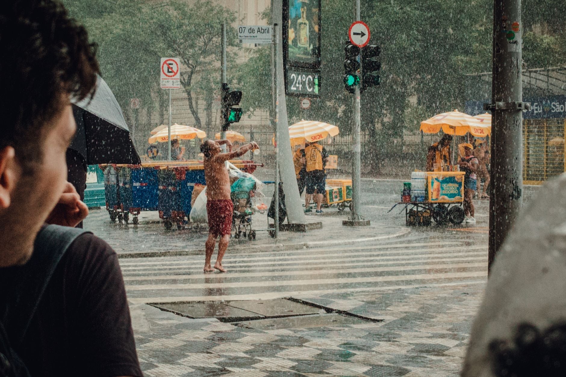 Previsão aponta quando o calor vai começar a diminuir e fazer o tempo virar no Brasil 1 Pessoas em São Paulo aproveitando um dia chuvoso com vendedores de rua coloridos, capturando a vida urbana.