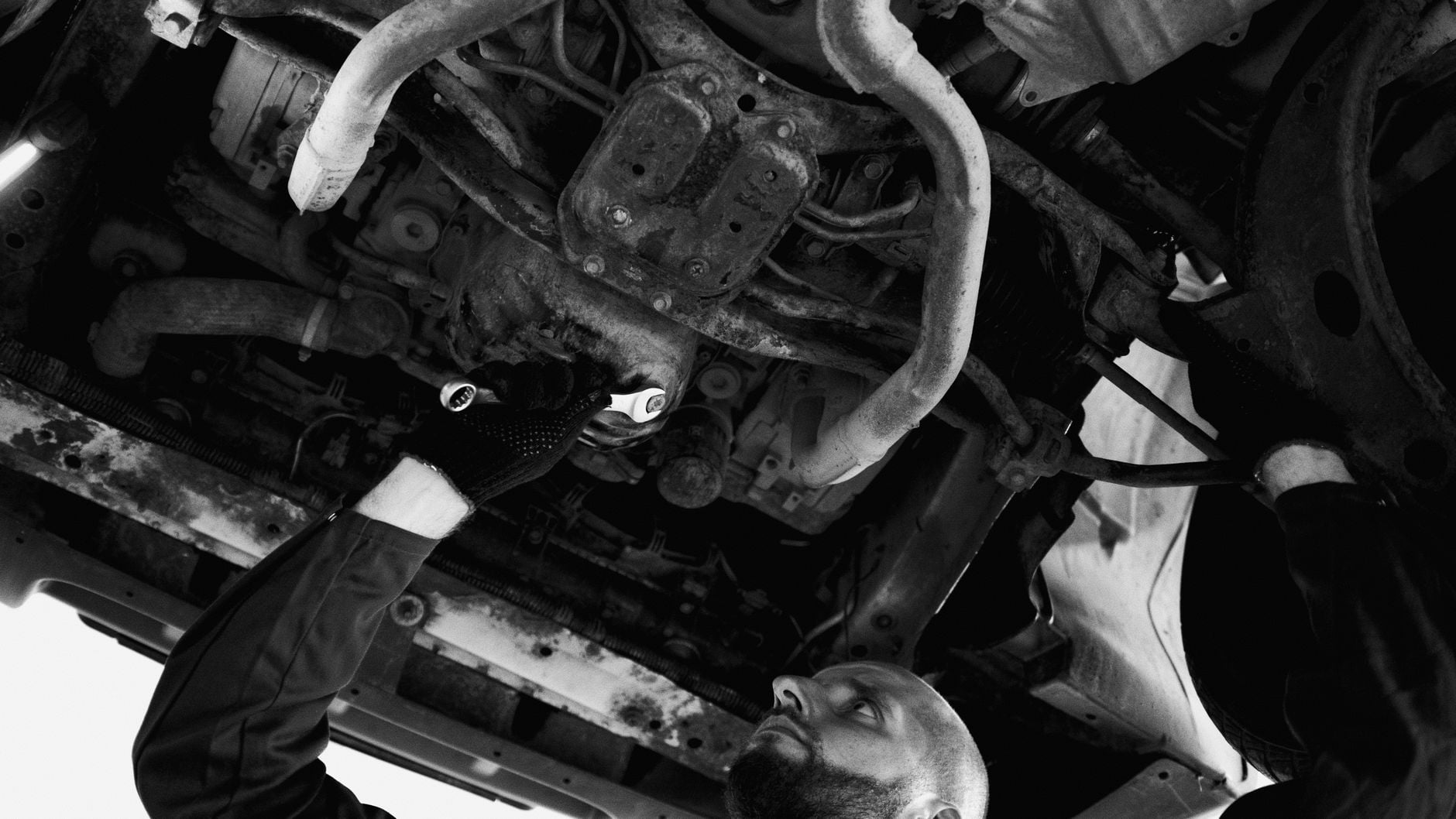 Mecânico realizando reparo no assoalho de um veículo em uma oficina de garagem.