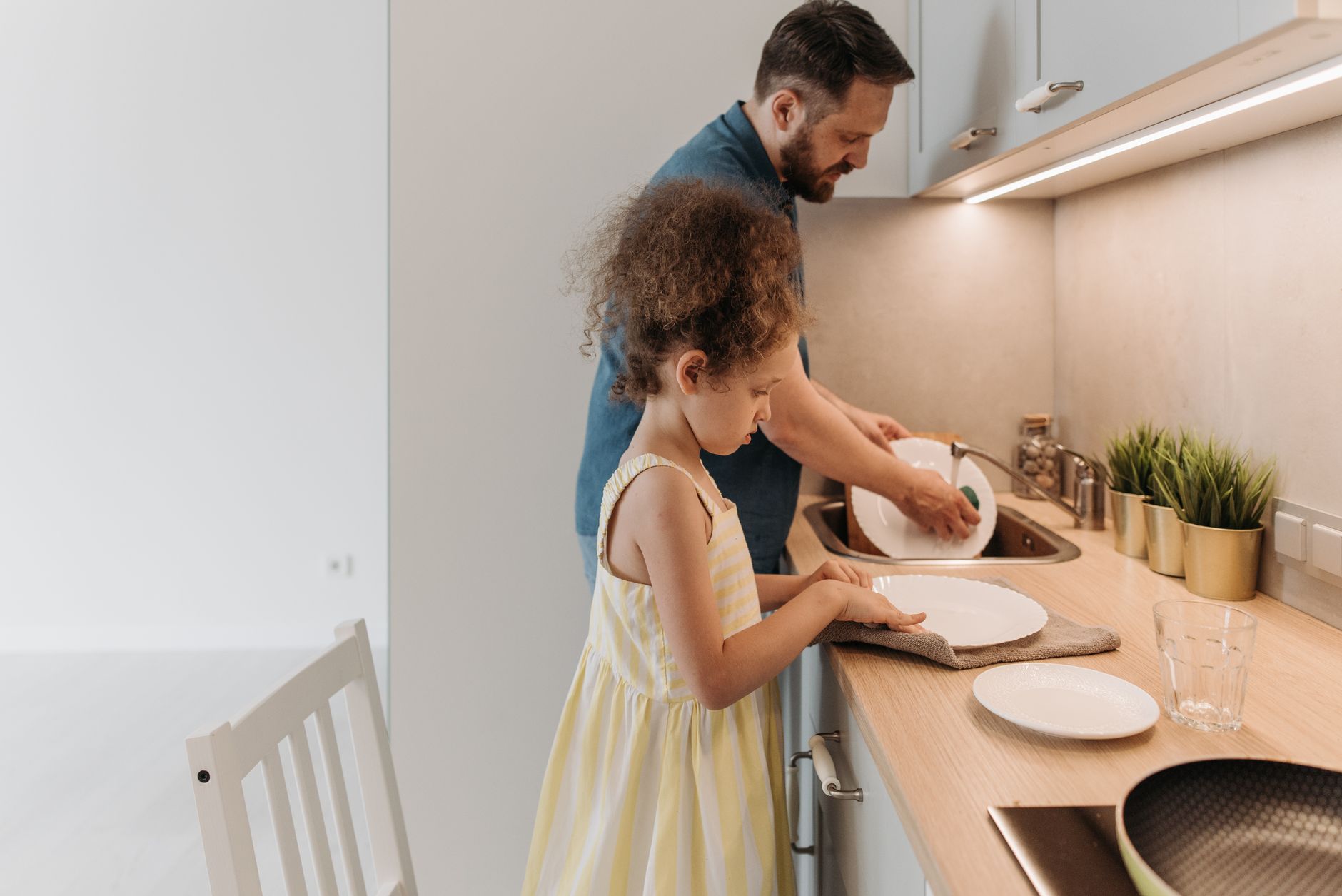 Você enxágua a louça antes de colocar na máquina? Psicologia explica por que tantas pessoas repetem esse hábito mesmo sem precisar 3 Pai e filha se conectando enquanto lavam a louça juntos em uma cozinha moderna.