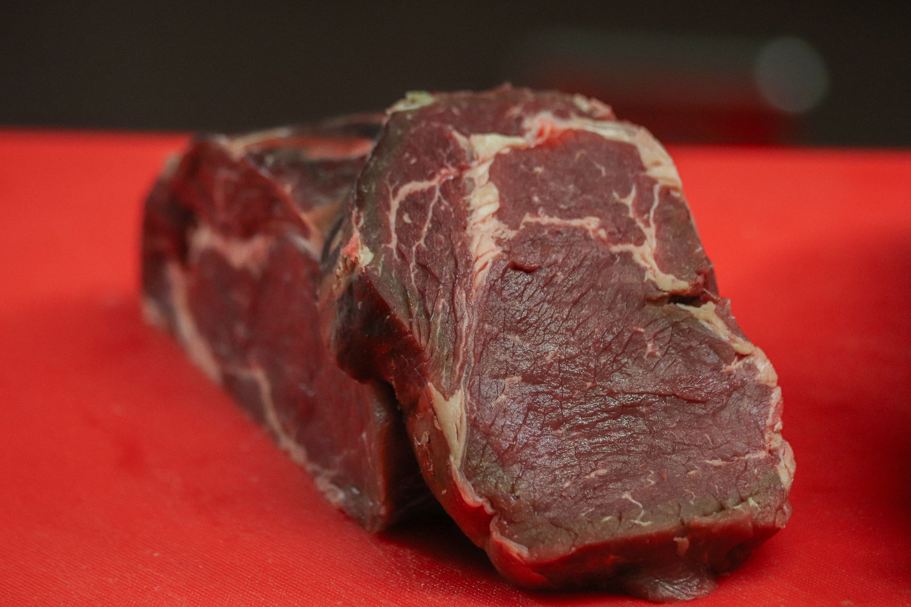 Chef revela qual corte de carne é o melhor para quem nunca preparou um bife em casa e explica por que ele é mais fácil de acertar mesmo quando a pessoa ainda não domina o ponto 3 Bife cru de alta qualidade em uma vibrante tábua de corte vermelha, pronto para preparação culinária.