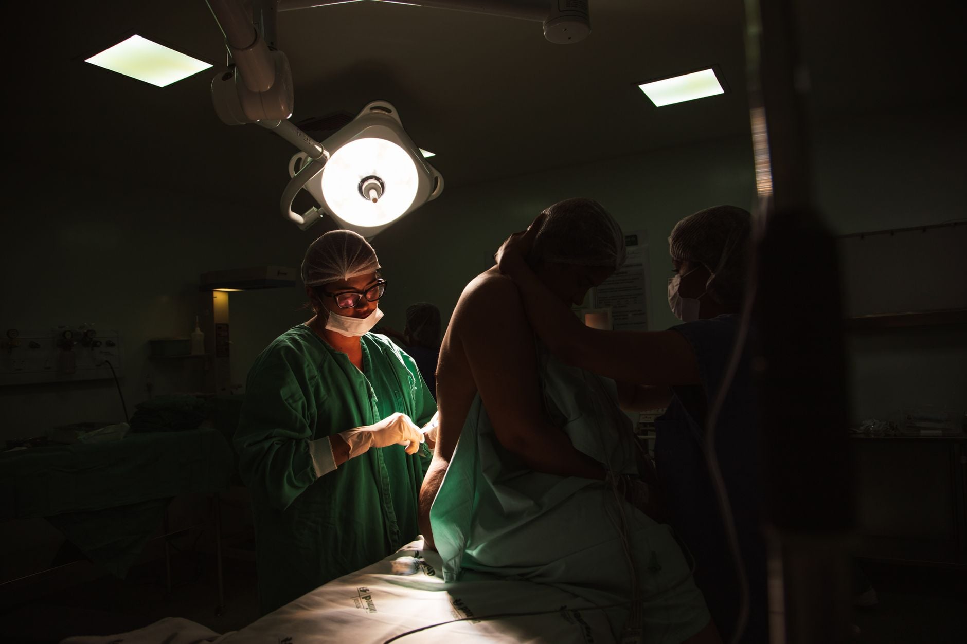 Cirurgia para retirar um cisto terminou com uma lesão inesperada em outra parte do corpo, dores e uma cicatriz permanente: após anos, paciente consegue indenização de R$ 20 mil na Justiça 3 Cirurgiões e enfermeiros se preparando para uma operação sob luzes cirúrgicas brilhantes.