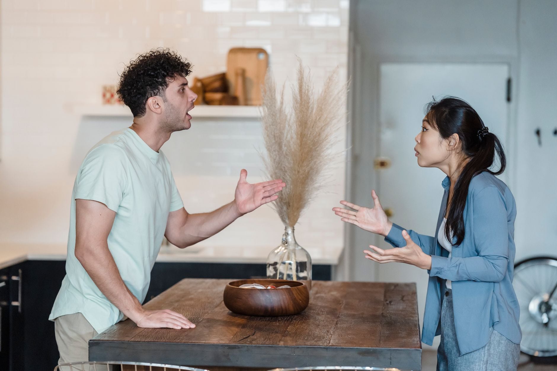 Um casal participa de uma discussão acalorada em uma mesa de madeira em um ambiente interno moderno.
