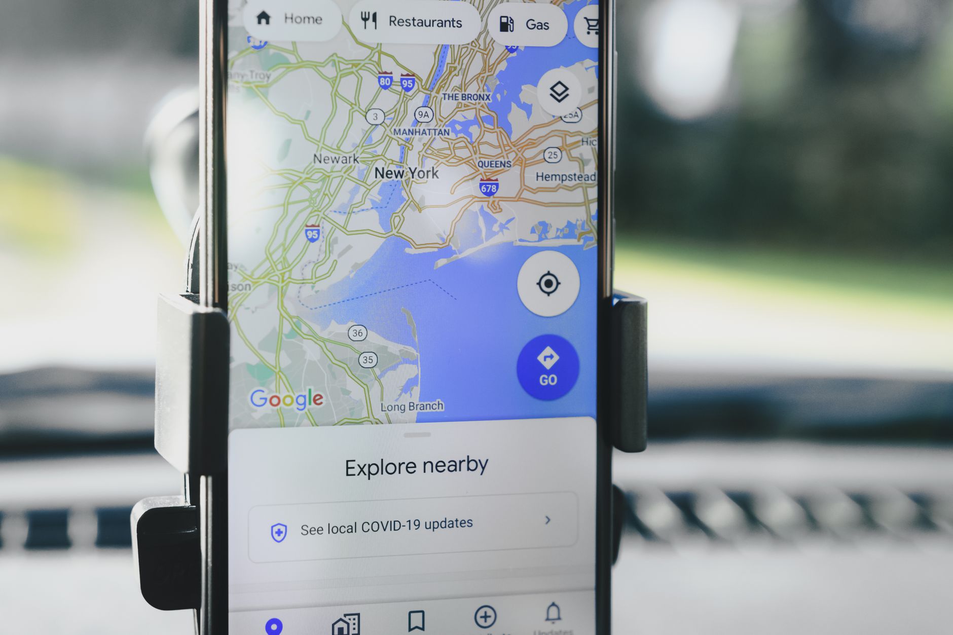 Um smartphone exibindo o mapa GPS de Nova Iorque preso a um suporte de carro durante o dia.