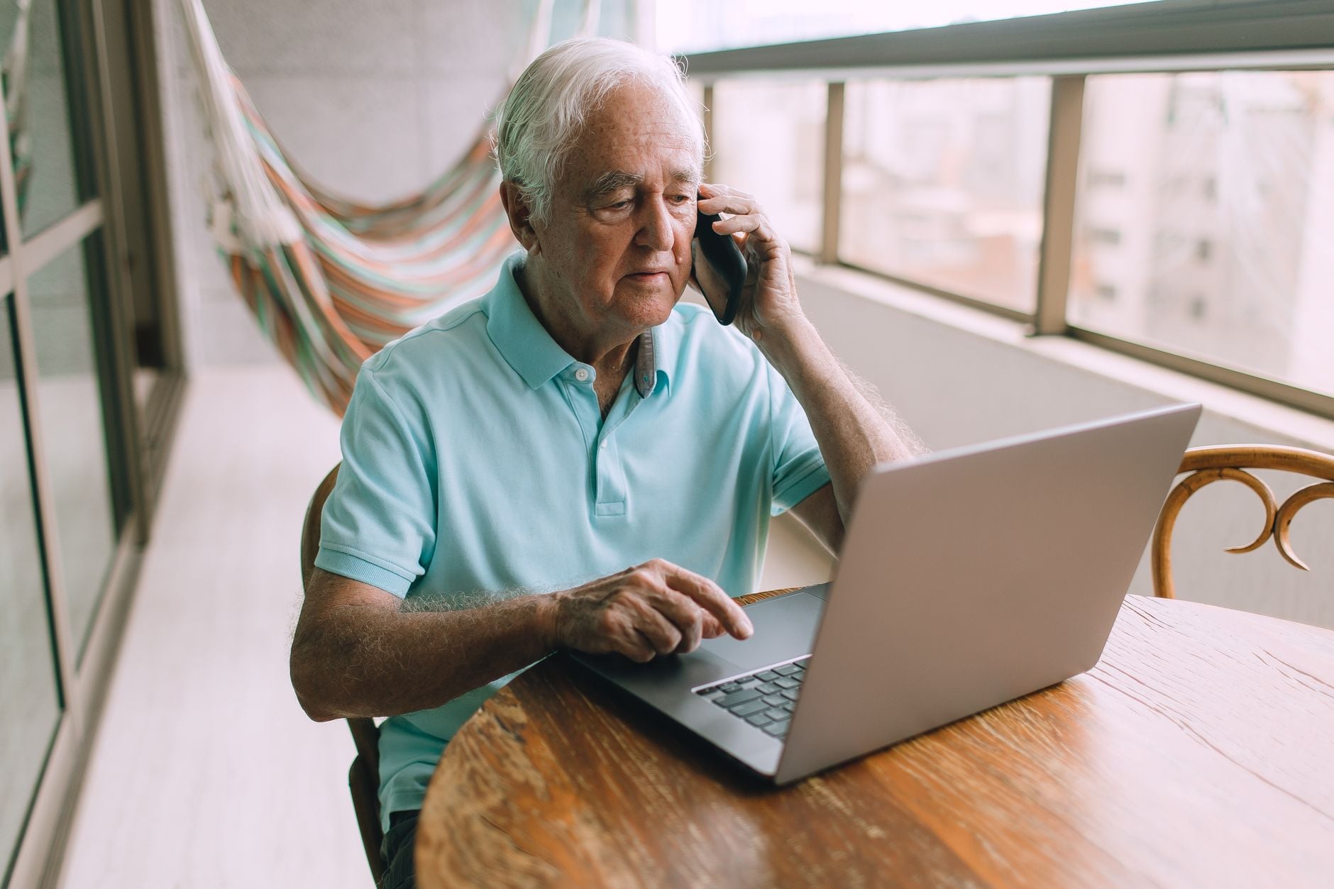 Eles não são contra a tecnologia e nem estão presos ao passado: pessoas criadas nos anos 60, 70 e 80 apenas lembram de quando as coisas funcionavam de outra maneira e por isso se recusam a aceitar mudanças que hoje parecem normais 6 Homem idoso multitarefando no telefone e no laptop em casa.