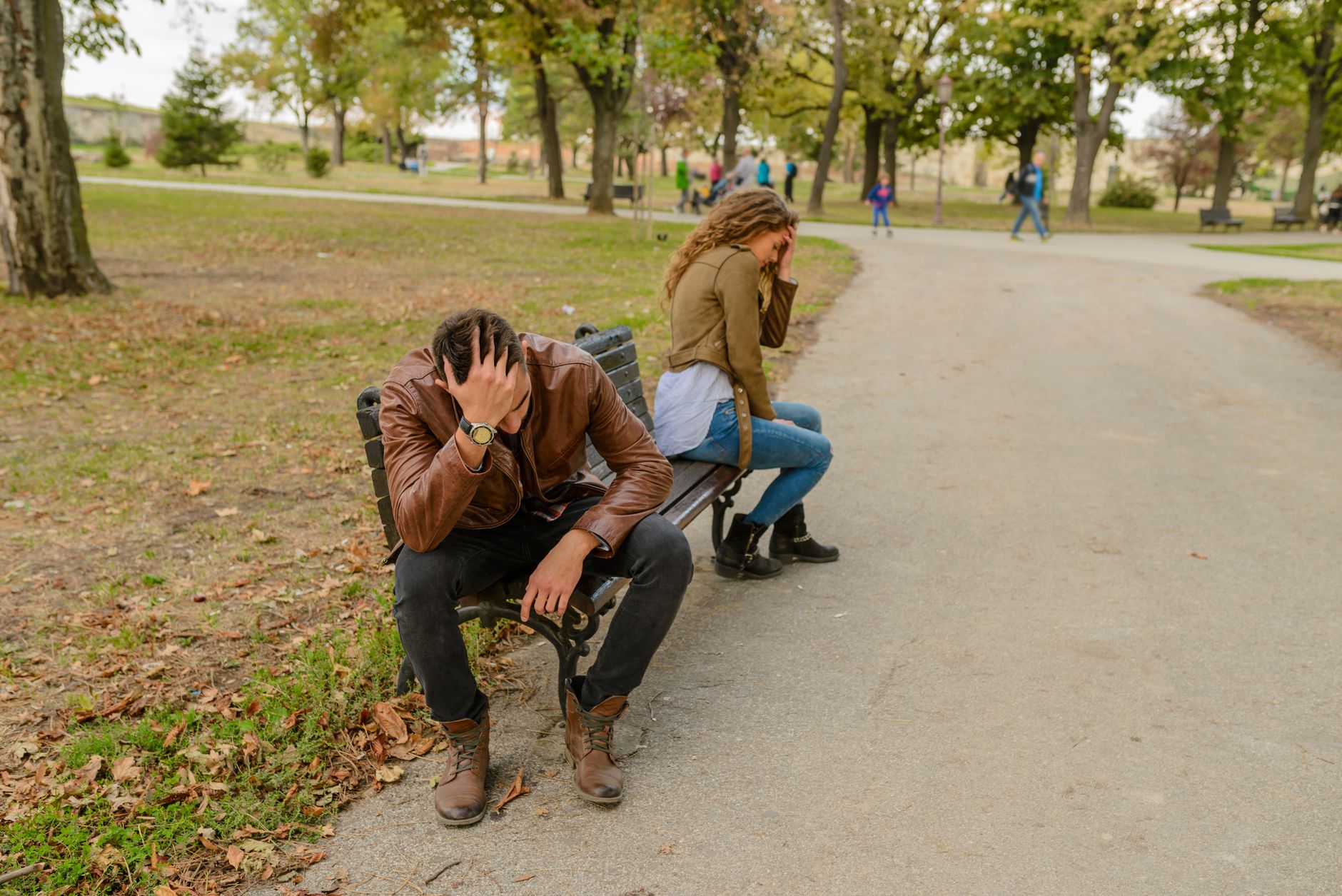 Em vez de insistir que a outra pessoa está errada, especialista recomenda duas etapas para conversar com quem nunca reconhece os próprios erros 4 Casal angustiado sentado separado em um banco de parque, de costas um para o outro, em um ambiente de parque público.