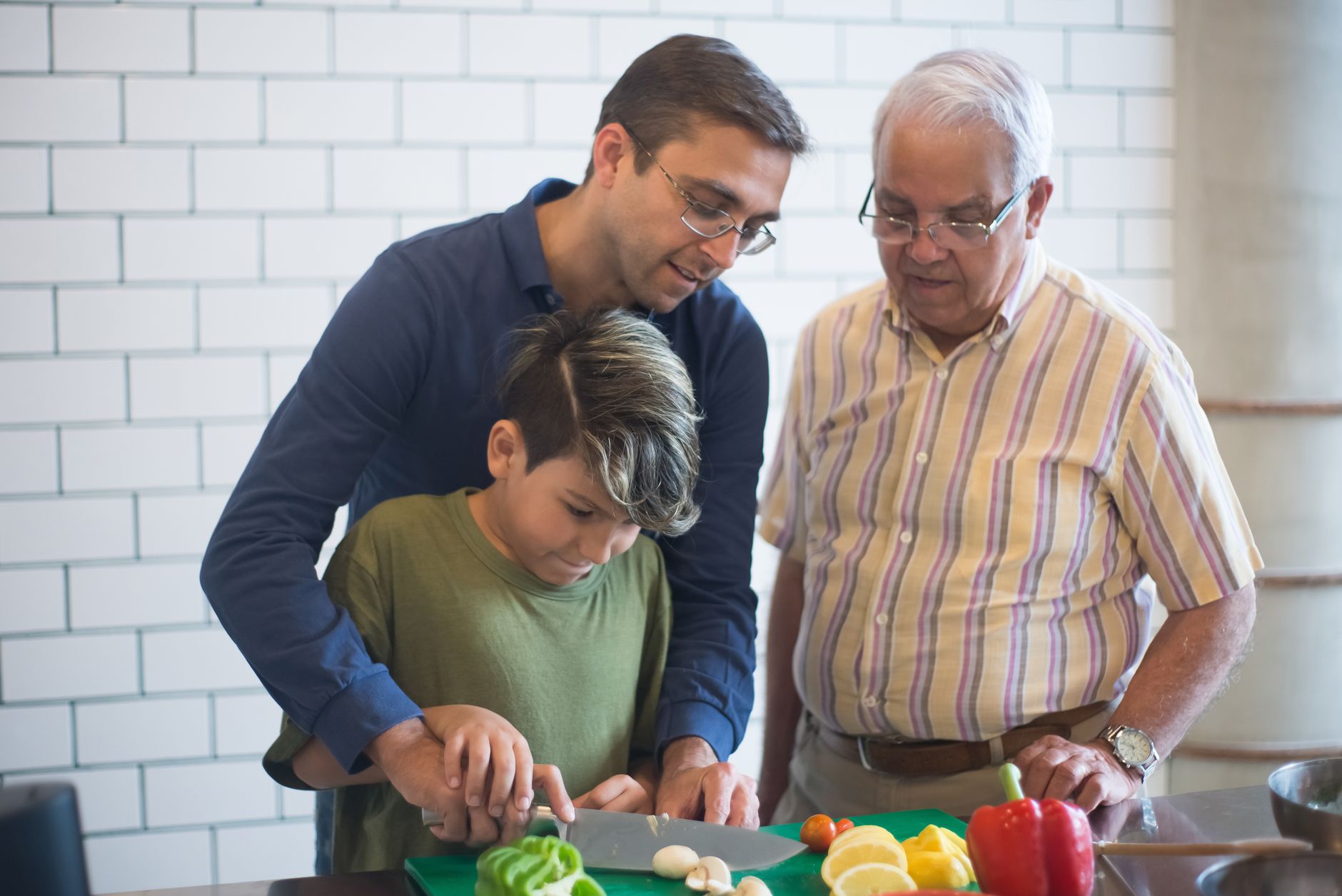 Família pode opinar sobre criação dos filhos, relacionamento e trabalho, mas pessoas emocionalmente maduras aprenderam a não transformar cada comentário em uma discussão 1 Três gerações cozinhando juntas, compartilhando habilidades e momentos familiares em uma cozinha iluminada.