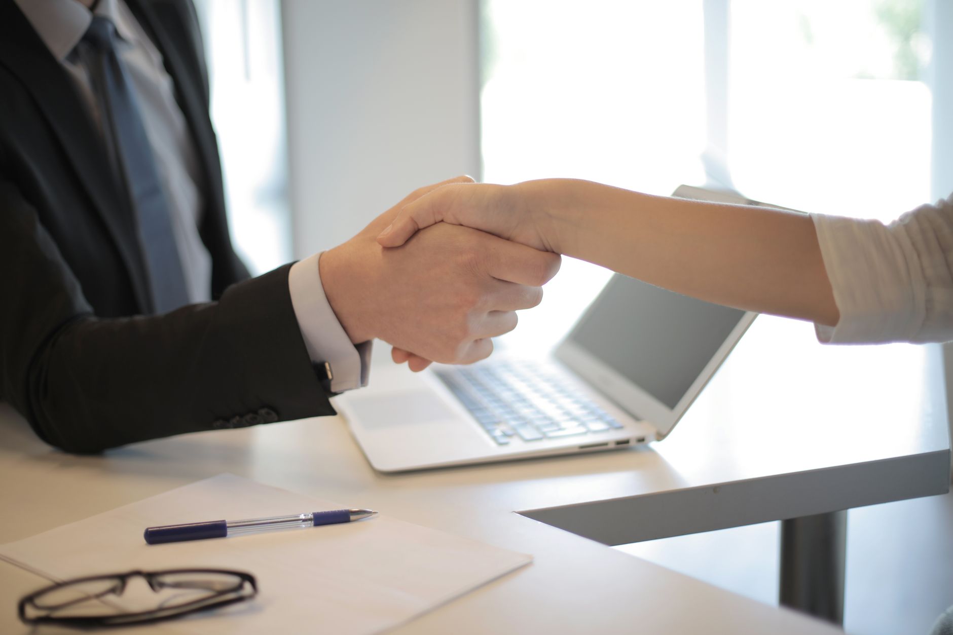 Fim da escala 6x1 pode mudar a rotina de empresas e trabalhadores no Brasil, criando novas formas de organizar jornadas e obrigando pequenos negócios a encontrar maneiras diferentes de manter a operação funcionando 2 Close-up de um aperto de mão profissional sobre um laptop durante uma reunião de negócios em um escritório.