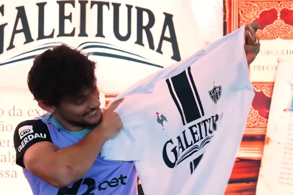 Gustavo Scarpa que é meia do Atlético mostra orgulhoso a camisa do clube do livro Galeitura