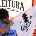 Gustavo Scarpa que é meia do Atlético mostra orgulhoso a camisa do clube do livro Galeitura