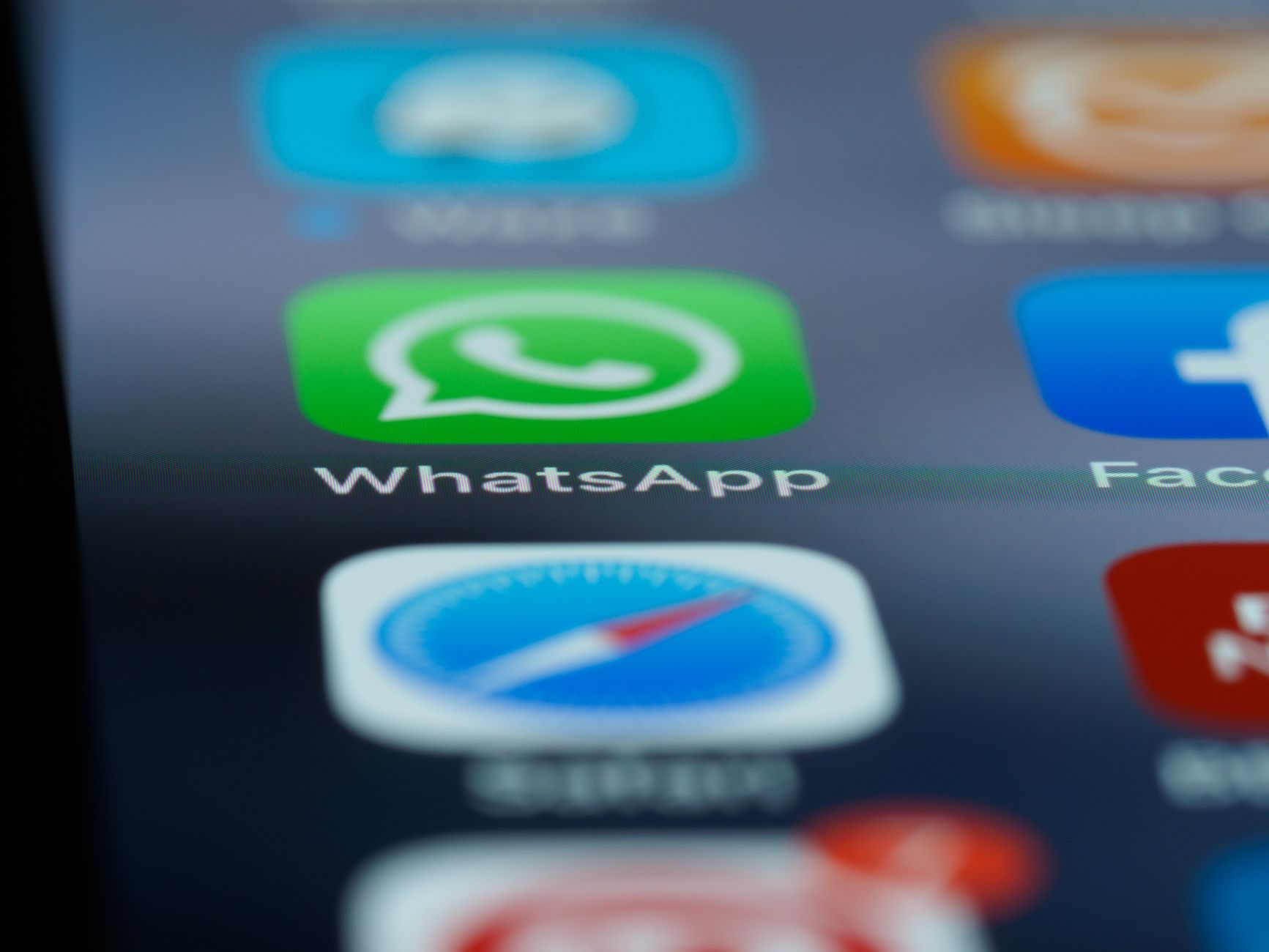 Close-up detalhado da tela inicial de um smartphone exibindo aplicativos populares como WhatsApp.