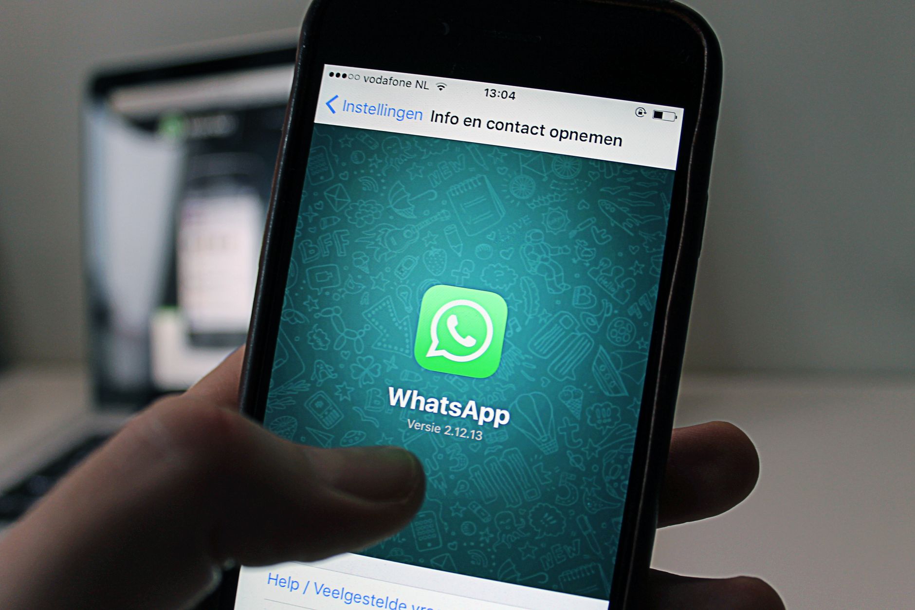 Um smartphone exibindo a tela do aplicativo WhatsApp segurado por uma pessoa.