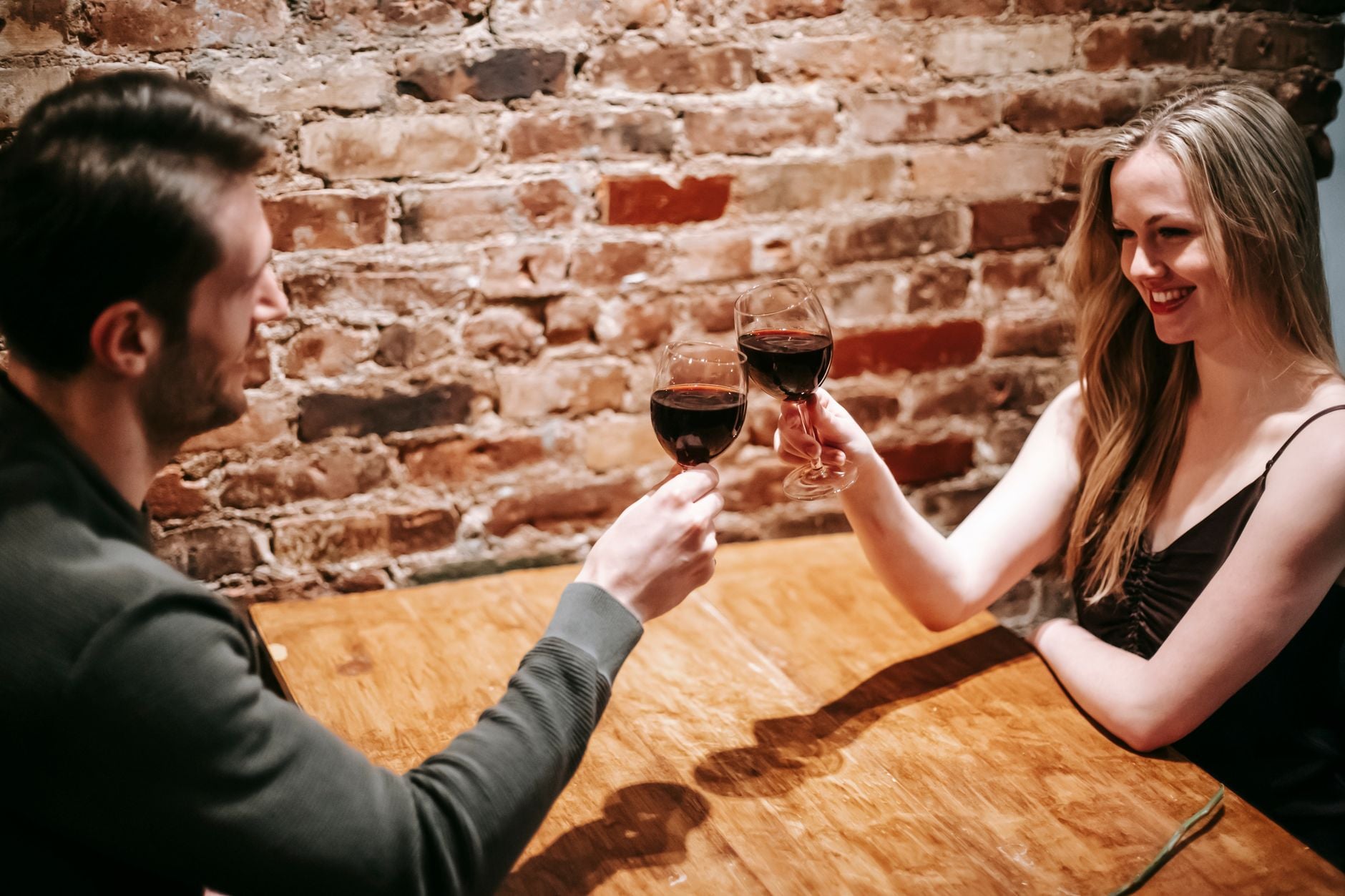 Casal desfrutando de uma noite romântica, brindando com vinho tinto em um restaurante aconchegante.