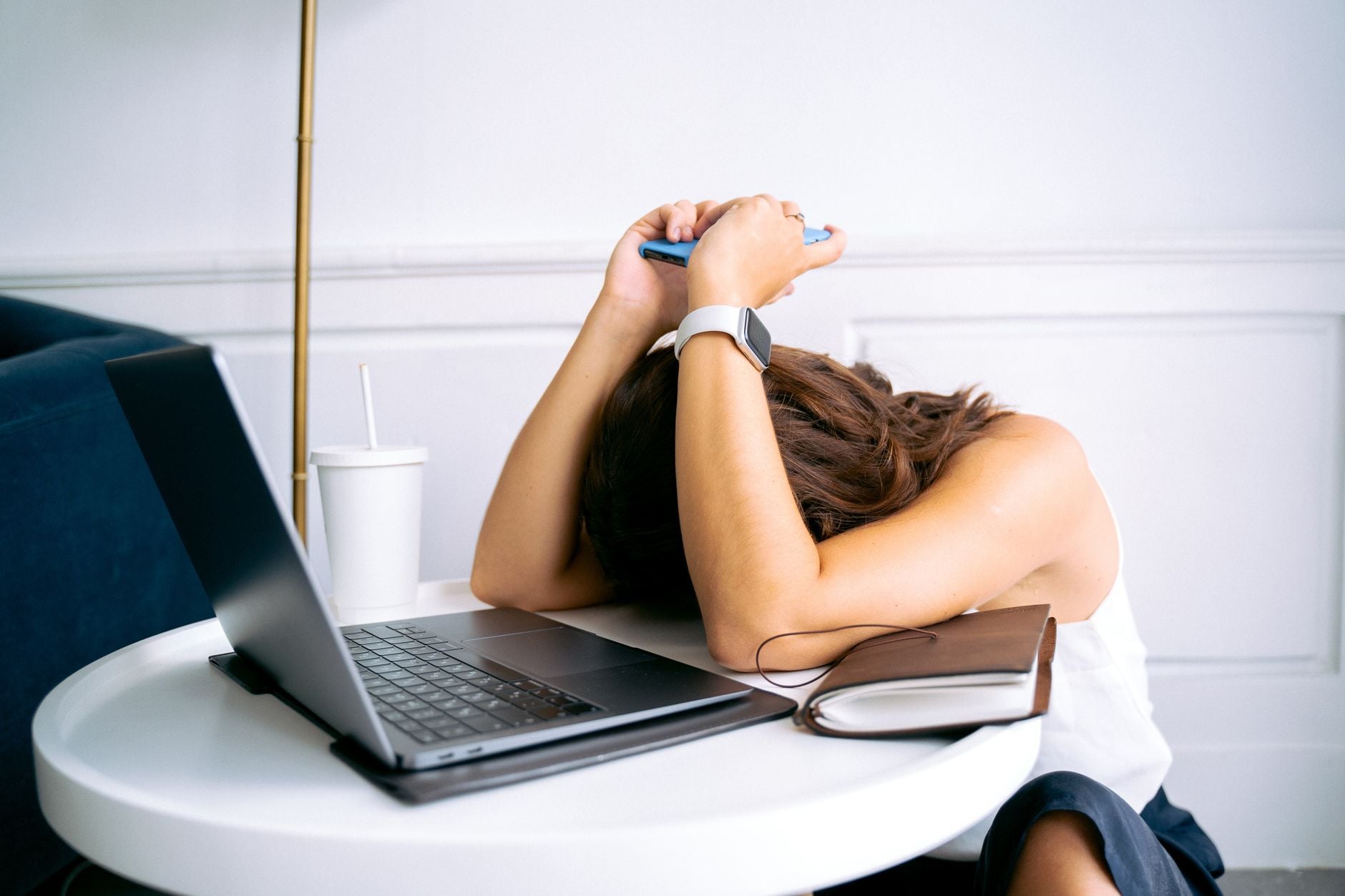 O que a psicologia diz sobre pessoas que deixam tudo para a última hora 4 Jovem mostrando estresse com laptop e celular na mesa, incorporando exaustão digital.