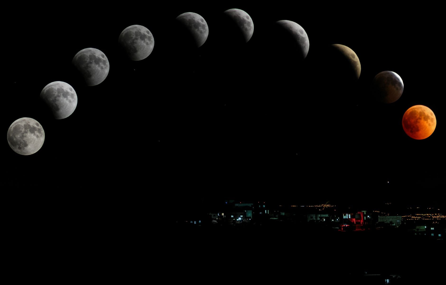 Sequência cativante de eclipse lunar apresentando a lua de sangue sobre a paisagem urbana.