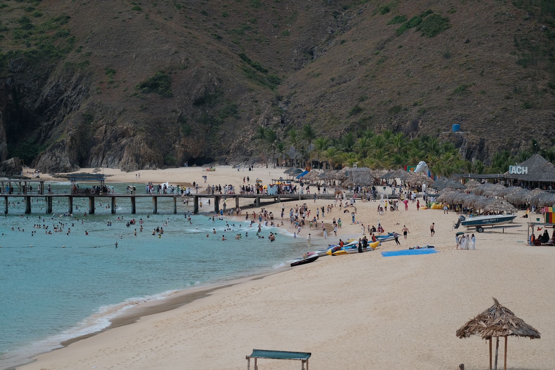 Uma cena vibrante de praia tropical com pessoas desfrutando de atividades aquáticas e relaxamento à beira-mar.