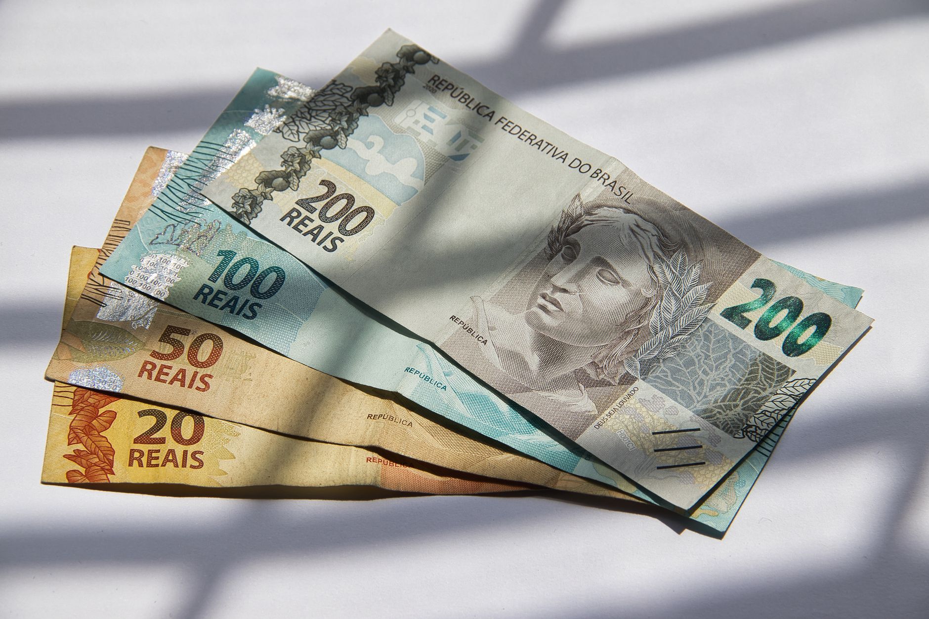 Qual é o salário de um senador no Brasil em 2026? 1 Vários reais brasileiros em luz do sol, destacando a variedade de moedas.