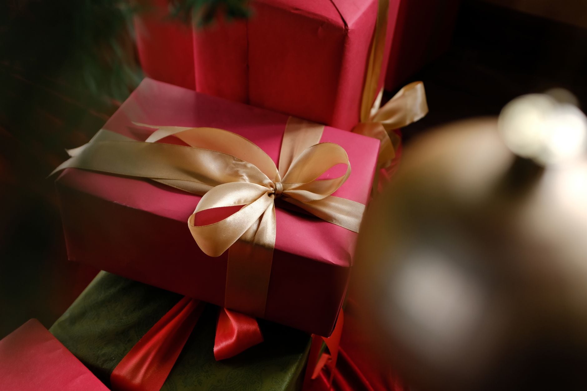 Caixas de presentes vermelhas lindamente embrulhadas com fitas douradas, perfeitas para celebrações de Natal.