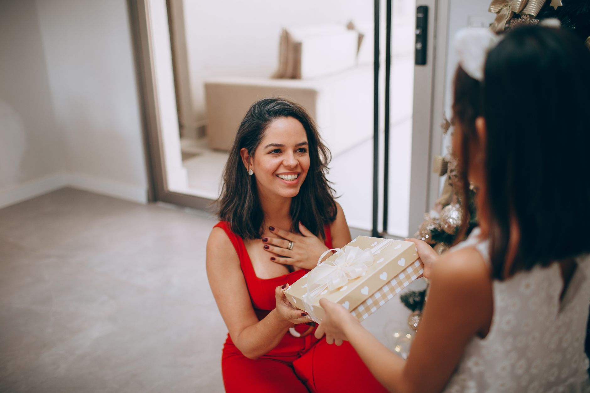 Quando os pais colocam responsabilidades de adultos sobre os filhos ainda pequenos, algumas crianças aprendem a cuidar de todo mundo menos delas mesmas e levam esse comportamento para a vida adulta 6 Mãe e filha trocam presentes junto à árvore de Natal, celebrando momentos festivos em casa.