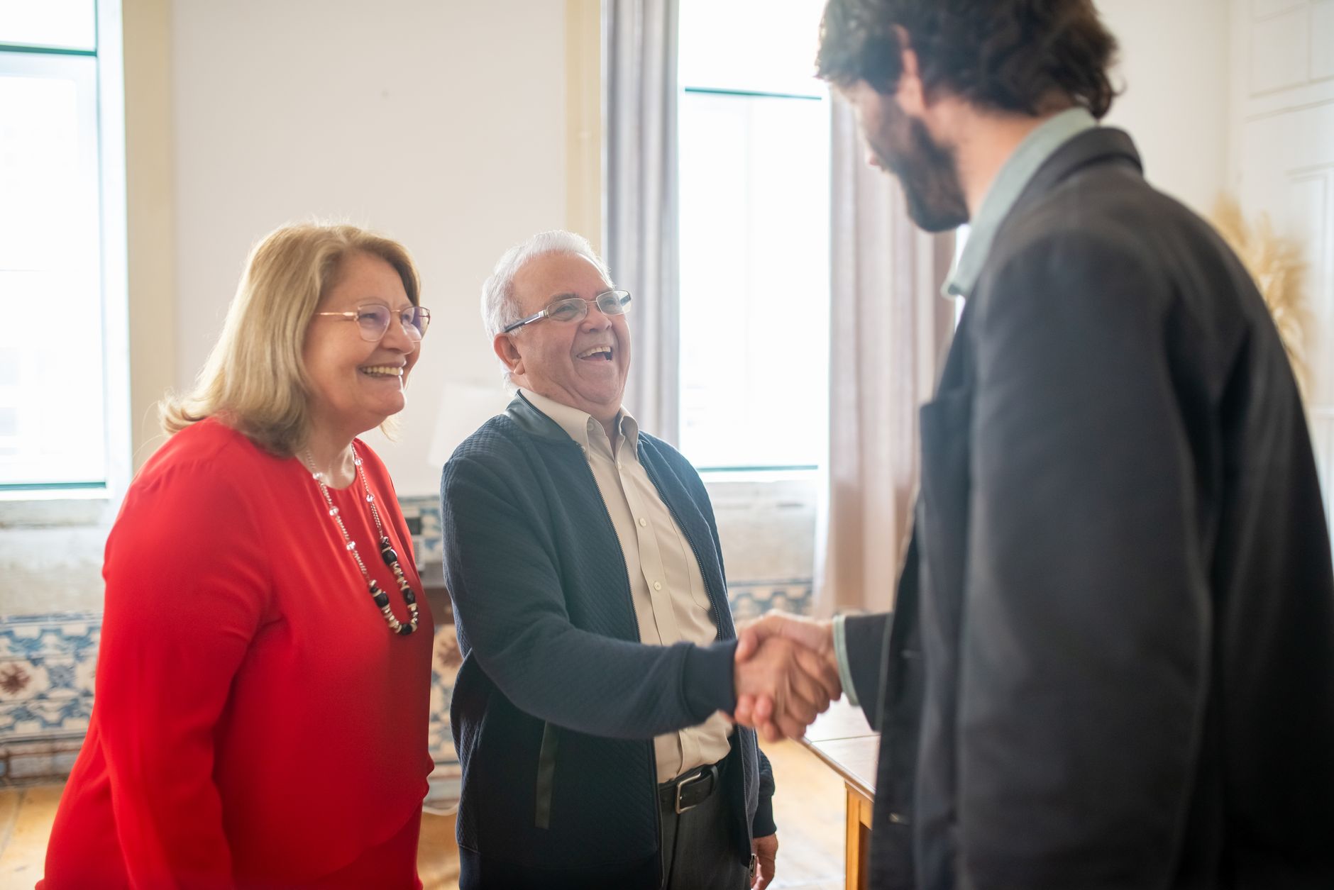Quando os pais colocam responsabilidades de adultos sobre os filhos ainda pequenos, algumas crianças aprendem a cuidar de todo mundo menos delas mesmas e levam esse comportamento para a vida adulta 8 Casal idoso se encontrando com um profissional em um ambiente de escritório iluminado, trocando sorrisos e um aperto de mãos.