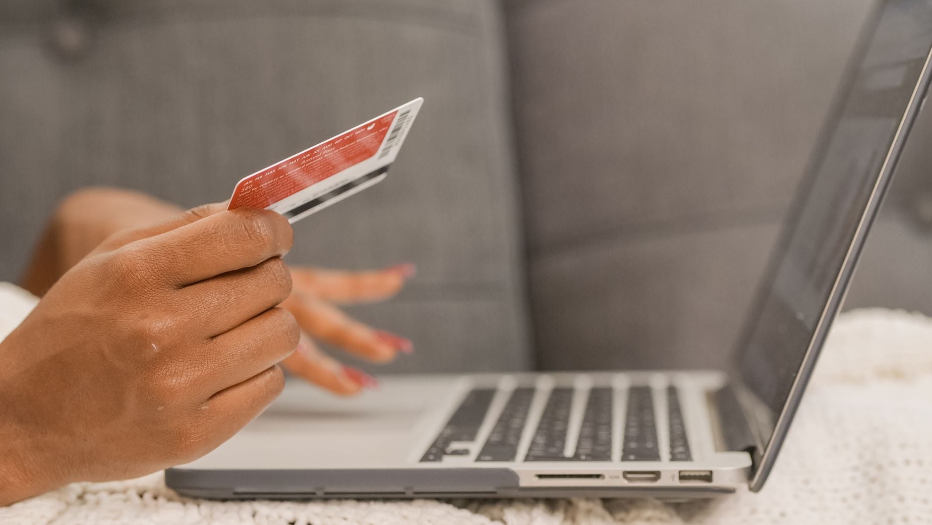 Você comprou roupas pela internet nos últimos dias? Ataque a lojas brasileiras capturava cartões e CPFs durante o pagamento 1 Close-up de uma pessoa usando um cartão de crédito para compras online em um laptop.