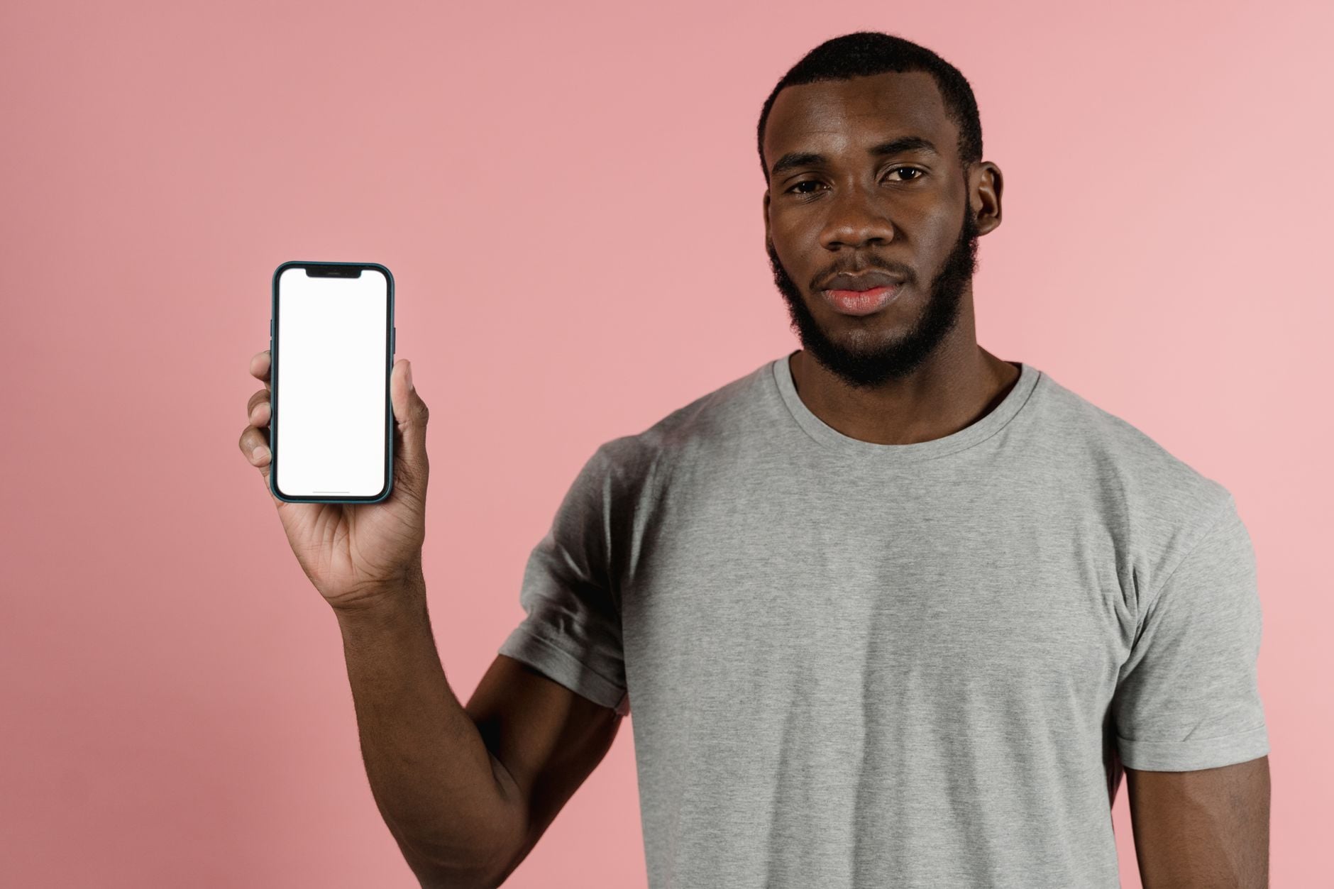 Você conversa sobre um produto e, pouco depois, aparece um anúncio dele no celular; será que os aplicativos estão ouvindo suas conversas? Veja como descobrir 1 Homem afro-americano apresentando uma tela em branco de smartphone contra um fundo rosa.