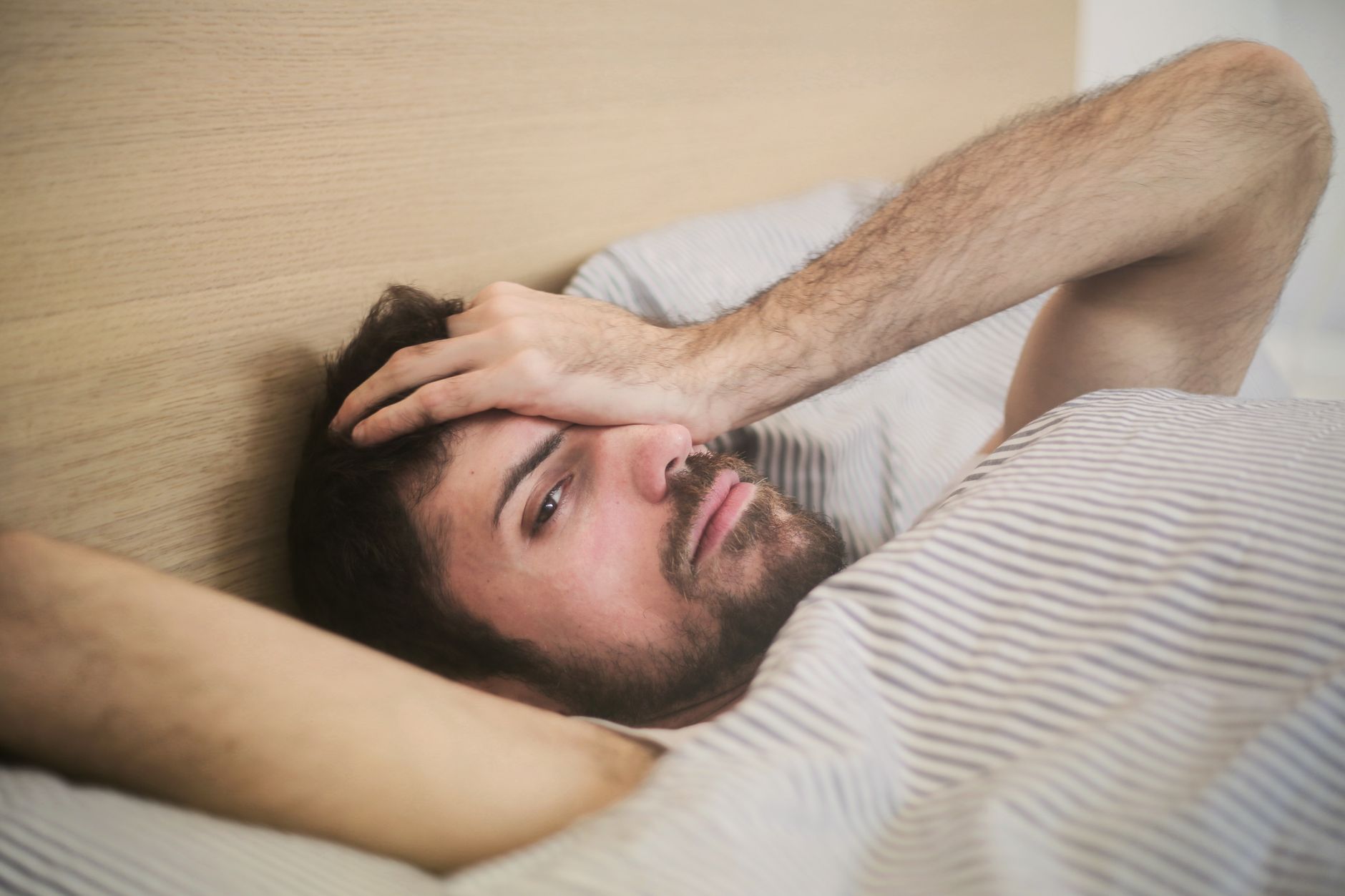Você costuma dormir depois do almoço e acorda ainda mais cansado? Especialista explica quanto tempo deve durar o cochilo da tarde e por que passar alguns minutos a mais pode atrapalhar sua disposição e o sono da noite 1 Um homem deitado na cama com uma expressão cansada, cena de relaxamento no início da manhã.
