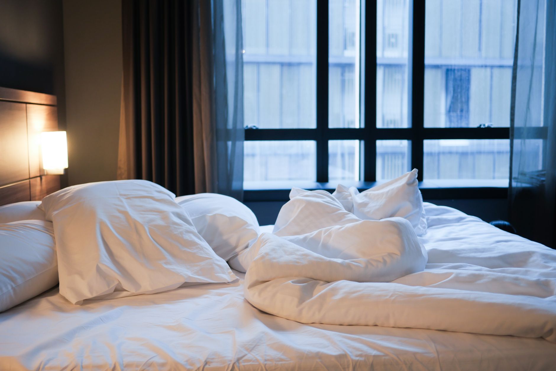 Você troca os lençóis da cama com que frequência? Especialistas dizem que muita gente está demorando mais do que deveria e explicam qual é o intervalo recomendado 2 Uma cama confortável desarrumada com lençóis brancos e travesseiros em um ambiente de hotel contemporâneo.
